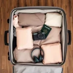 Suitcase packed with travel essentials including camera and passport.