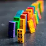 Colorful dominoes falling in a row, representing how inconsistency ruins plans through chain reactions.