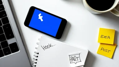 Smartphone with Facebook open, surrounded by post-planning notes and coffee mug on a desk