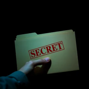 2121125 Hand opening a folder labeled 'SECRET' with dramatic lighting to evoke mystery
